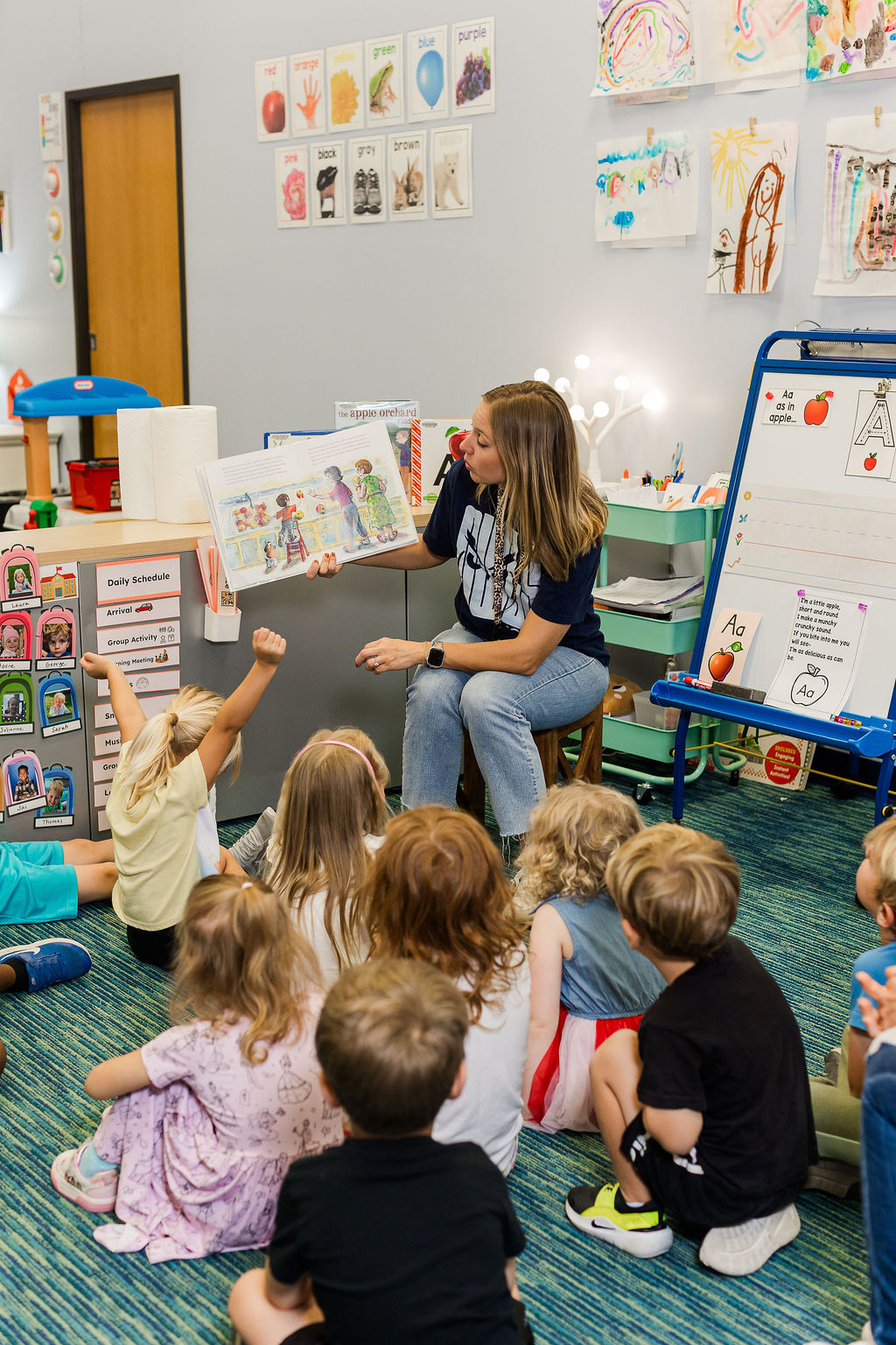 Teacher reading a picture book to a group of young students