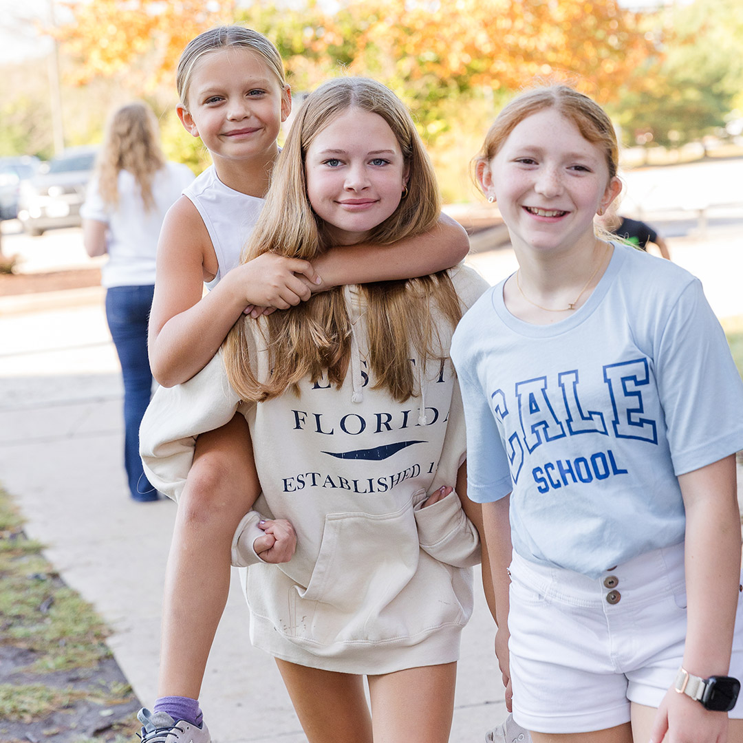 Three students at CALE, one carrying another on her back