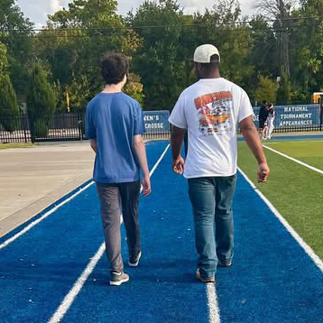 Two high school students casually walking down the race track together